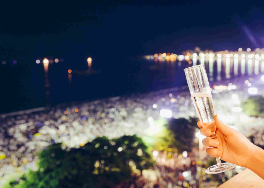 Pessoa com taça de espumante em Copacabana no Réveillon